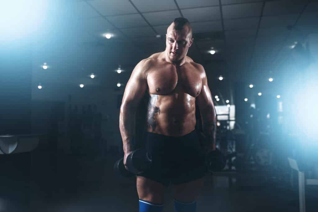 Strong male bodybuilder with pancakes from barbell